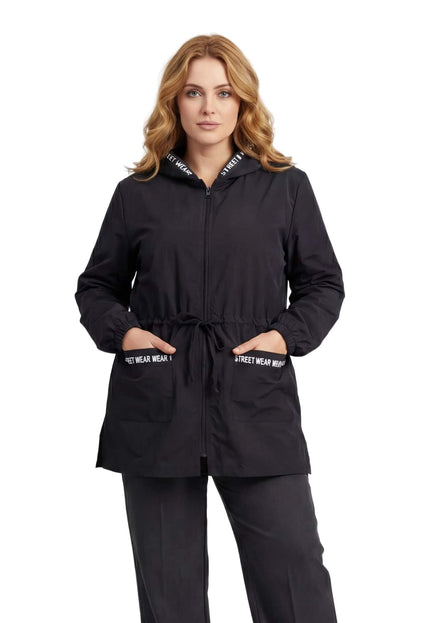 Μαύρο γυναικείο αντιανεμικό μπουφάν plus size με κουκούλα και τσέπες που φέρουν διακοσμητική επιγραφή street wear, σε άνετη γραμμή και μπροστινή λήψη.