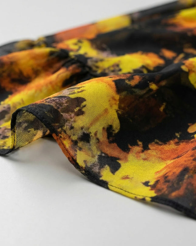 Κοντινή λεπτομέρεια στο τελείωμα από το γυναικείο φόρεμα μεγάλα μεγέθη, αναδεικνύοντας το σιφόν ύφασμα με το αφηρημένο μαύρο και κίτρινο μοτίβο.