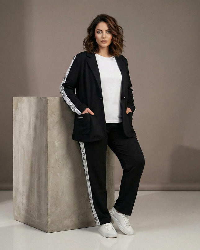 Μαύρο καθημερινό γυναικείο σετ σακάκι και παντελόνι σε μεγάλα μεγέθη, διακοσμημένο με λευκές ρίγες στα πλαϊνά. Ολόσωμη λήψη που παρουσιάζει την άνετη εφαρμογή.