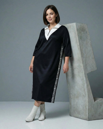 Μαύρο σπορ κομψό φόρεμα μεγάλα μεγέθη με λευκό γιακά, λειτουργικό φερμουάρ και διακοσμητικές πλαϊνές ρίγες, σε ολόσωμη λήψη με λευκά μποτάκια.