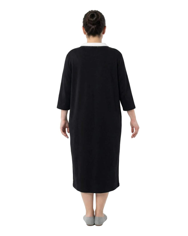 Πίσω όψη από μαύρο σπορ φόρεμα μεγάλα μεγέθη με ίσια γραμμή και μανίκια 7/8. Διακρίνεται η άνετη εφαρμογή στην πλάτη και το μήκος κάτω από το γόνατο σε λευκό φόντο.