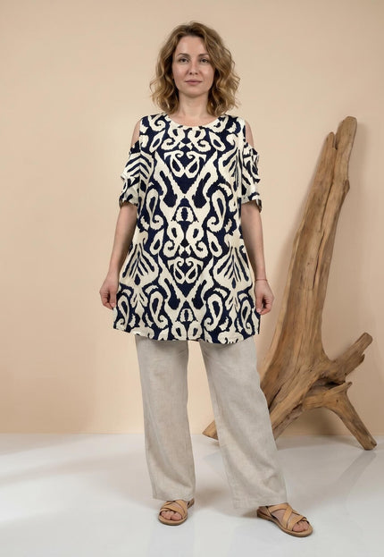 Ολόσωμη λήψη: Μπεζ καλοκαιρινή τουνίκ σε μεγάλα μεγέθη, με σκούρο αφηρημένο μοτίβο και ανοιχτούς ώμους, φορεμένη από μοντέλο.