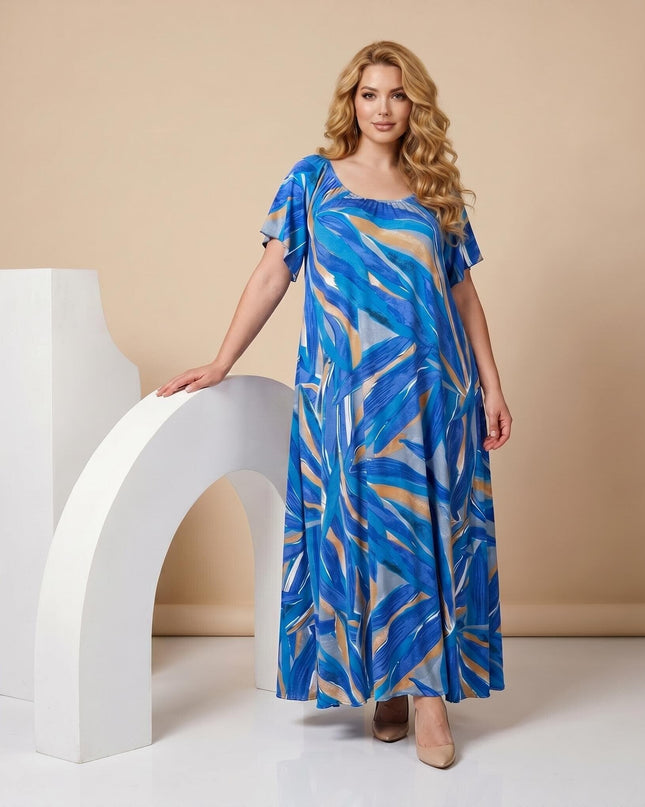 Ολόσωμη λήψη. Μπλε επίσημο μάξι φόρεμα plus size με εντυπωσιακό αφηρημένο μοτίβο, αέρινη εφαρμογή και κοντά μανίκια τύπου πεταλούδα.