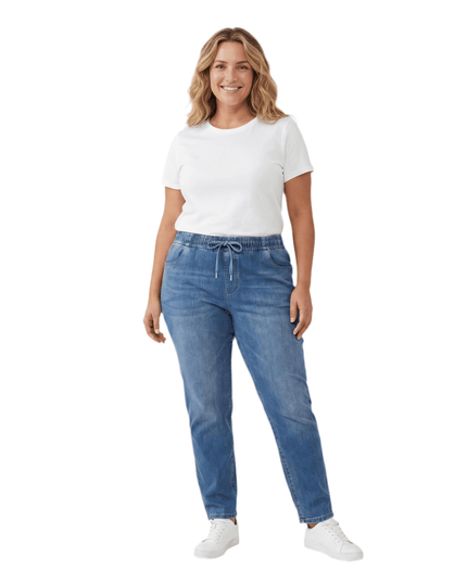 Μπλε γυναικείο τζιν από tencel και βαμβάκι σε μεγάλα μεγέθη, με λάστιχο και κορδόνι στη μέση. Ολόσωμη λήψη του ρούχου φορεμένο από μοντέλο σε λευκό φόντο.