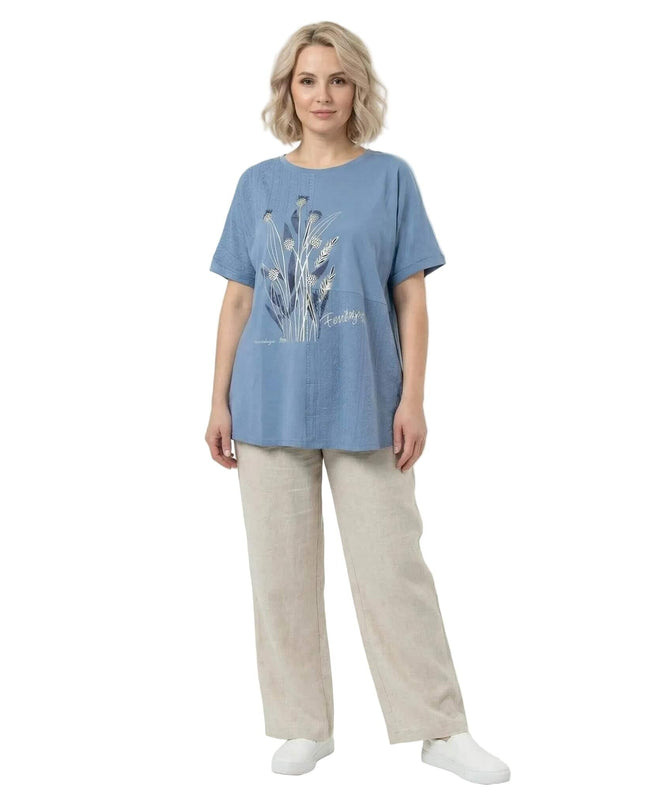 Ολόσωμη λήψη της μπλε καλοκαιρινής τουνίκ μεγάλα μεγέθη. Εμπριμέ με λουλούδια και δαντέλα, φορεμένη από μοντέλο σε λευκό φόντο.