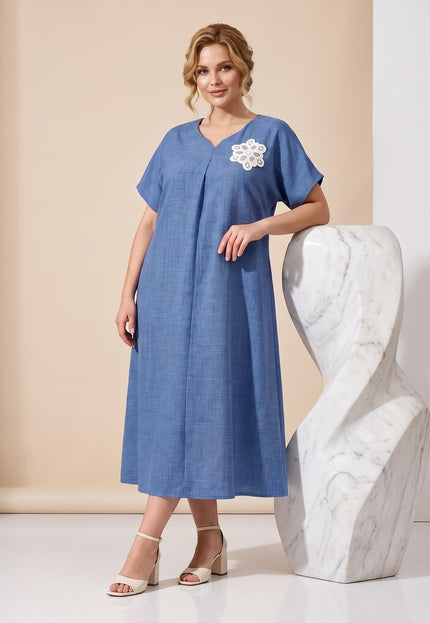 Ολόσωμη λήψη με μπλε μάξι επίσημο φόρεμα plus size. Διαθέτει V-ντεκολτέ, κοντά μανίκια και εντυπωσιακό λευκό φλοράλ κέντημα στο στήθος.