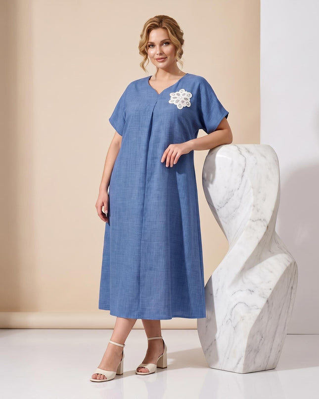 Ολόσωμη λήψη με μπλε μάξι επίσημο φόρεμα plus size. Διαθέτει V-ντεκολτέ, κοντά μανίκια και εντυπωσιακό λευκό φλοράλ κέντημα στο στήθος.