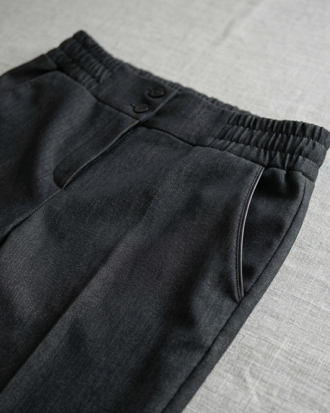 Детайл отблизо на официален дамски черен панталон, показващ еластичната талия, страничния джоб и закопчаването с две копчета.
