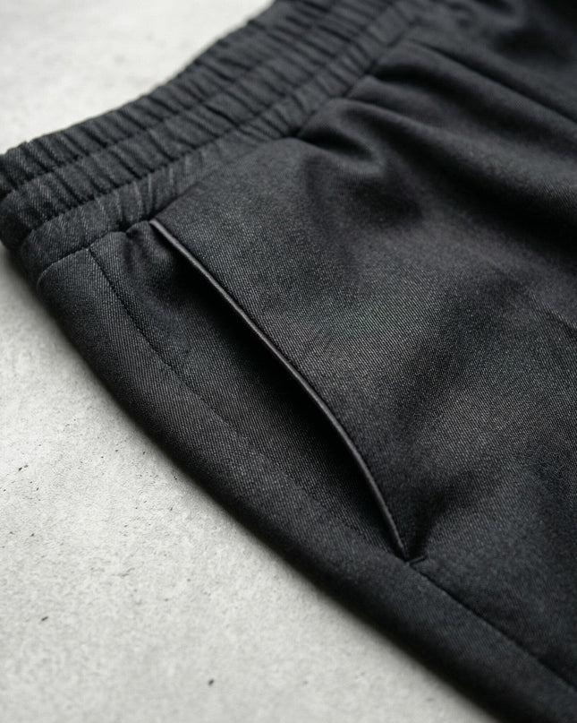 Детайл отблизо на страничен джоб и ластик на талията на официален дамски черен панталон, показващ текстурата на плата.