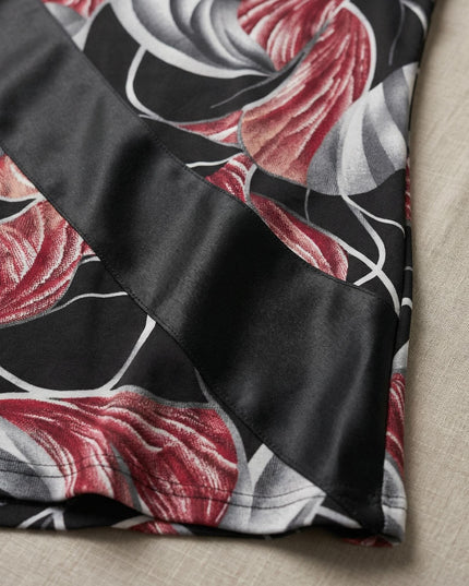 Детайлен кадър на официална разкроена макси туника, акцентиращ върху диагоналната лента от еко кожа и материята с червено-бял флорален принт.