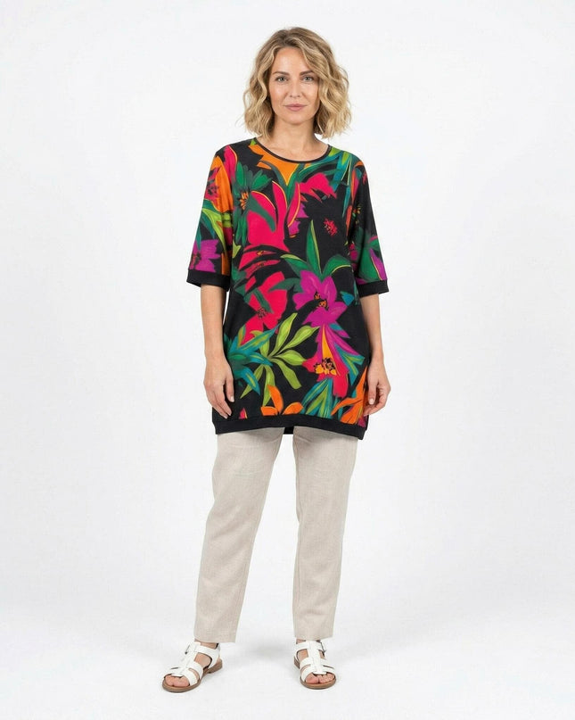 Ολόσωμη λήψη σε λευκό φόντο: Πολύχρωμη καλοκαιρινή τουνίκ σε μεγάλα μεγέθη, με μαύρη βάση, τροπικό φλοράλ σχέδιο και κοντά μανίκια.