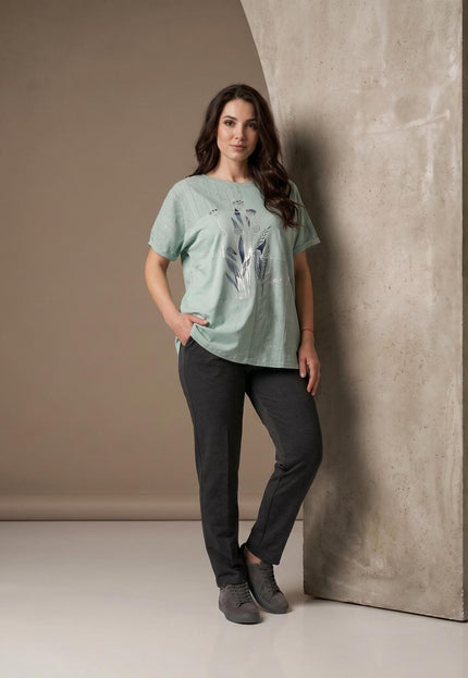 Ολόσωμη λήψη μοντέλου που φοράει πράσινη βαμβακερή τουνίκ σε μεγάλα μεγέθη, με φλοράλ σχέδιο και λεπτομέρειες δαντέλας στους ώμους.