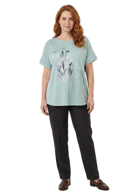 Ολόσωμη λήψη σε λευκό φόντο: Πράσινη καθημερινή τουνίκ σε μεγάλα μεγέθη με φλοράλ σχέδιο και δαντέλα, συνδυασμένη με σκούρο παντελόνι.