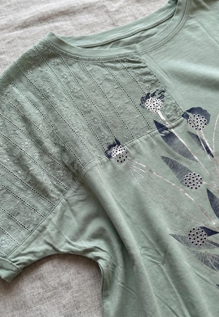 Κοντινή λεπτομέρεια στο μανίκι: Πράσινη καθημερινή βαμβακερή τουνίκ σε μεγάλα μεγέθη, διακοσμημένη με δαντέλα και φλοράλ απλικέ.