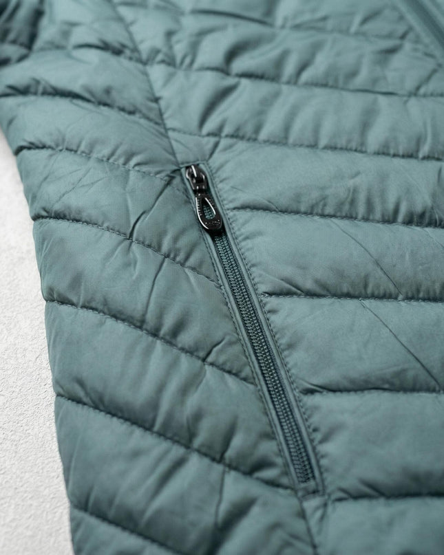 Κοντινή λεπτομέρεια σε πράσινο γυναικείο μπουφάν plus size, εστιάζοντας στην πλαϊνή τσέπη με το φερμουάρ και τις διαγώνιες καπιτονέ ραφές.