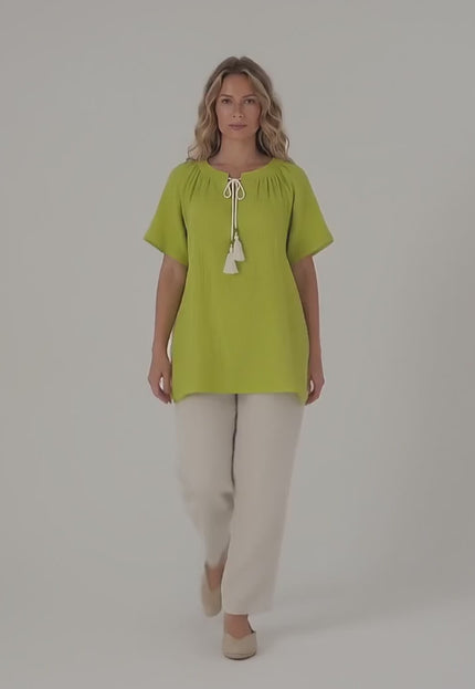Ένα plus size μοντέλο περπατάει αργά προς την κάμερα σε περιβάλλον στούντιο με ουδέτερο φόντο φορώντας το προϊόν Πράσινη βαμβακερή τουνίκ σε άνετη γραμμή μεγάλα μεγέθη