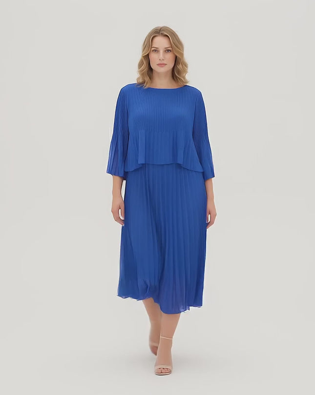 Ένα plus-size μοντέλο περπατάει αργά προς την κάμερα σε περιβάλλον στούντιο με ουδέτερο φόντο φορώντας το προϊόν Κομψό Επίσημο Πλισέ Φόρεμα Μπλε Ρουά Plus Size