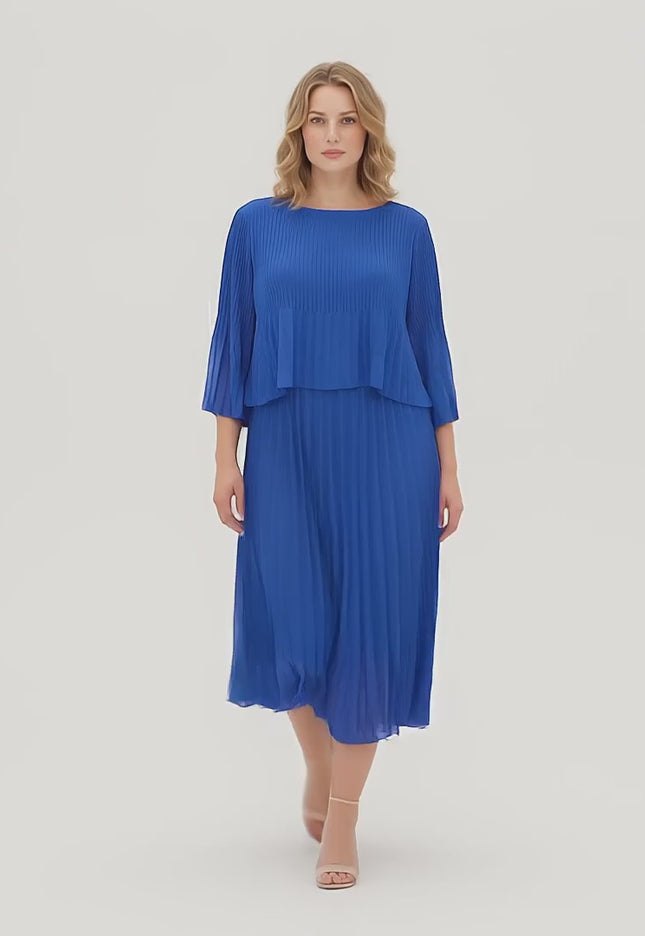 Ένα plus-size μοντέλο περπατάει αργά προς την κάμερα σε περιβάλλον στούντιο με ουδέτερο φόντο φορώντας το προϊόν Κομψό Επίσημο Πλισέ Φόρεμα Μπλε Ρουά Plus Size