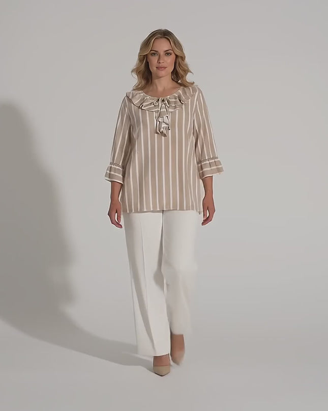 Βίντεο σε περιβάλλον στούντιο που δείχνει ένα γυναικείο μοντέλο να περπατάει αργά προς την κάμερα φορώντας το ρούχο Επίσημη εβαζέ ριγέ τουνίκ σε μπεζ και λευκό για μεγάλα μεγέθη