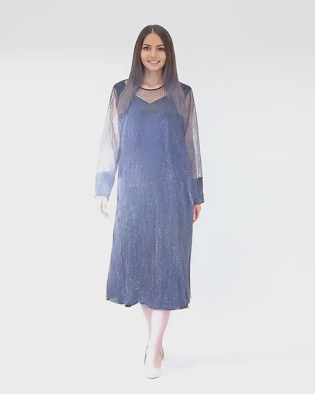 Ένα plus-size γυναικείο μοντέλο περπατάει αργά προς την κάμερα σε περιβάλλον στούντιο με ουδέτερο φόντο φορώντας το Μακρυ επίσημο φόρεμα με κλος γραμμή