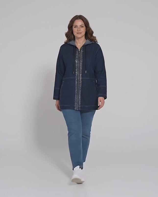 Σε περιβάλλον στούντιο ένα μοντέλο περπατάει αργά προς την κάμερα φορώντας το Μακρύ σκούρο μπλε τζιν μπουφάν με κουκούλα σε μεγάλα μεγέθη