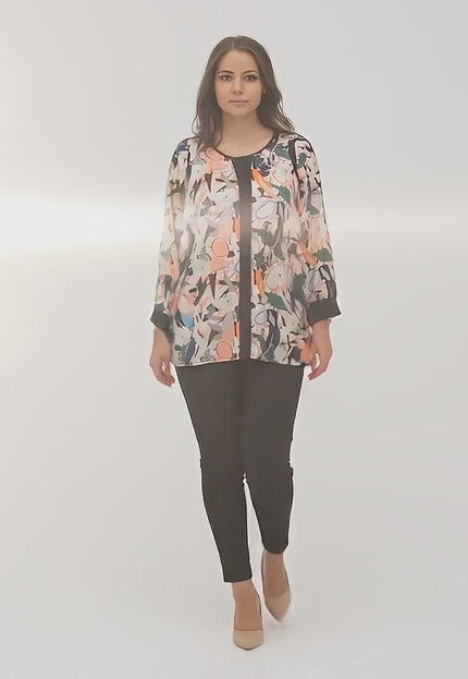 Ένα plus-size μοντέλο περπατάει αργά προς την κάμερα σε περιβάλλον στούντιο με ουδέτερο φόντο φορώντας το προϊόν Στιλάτη τουνίκ με πολύχρωμο σχέδιο σε μεγάλα μεγέθη