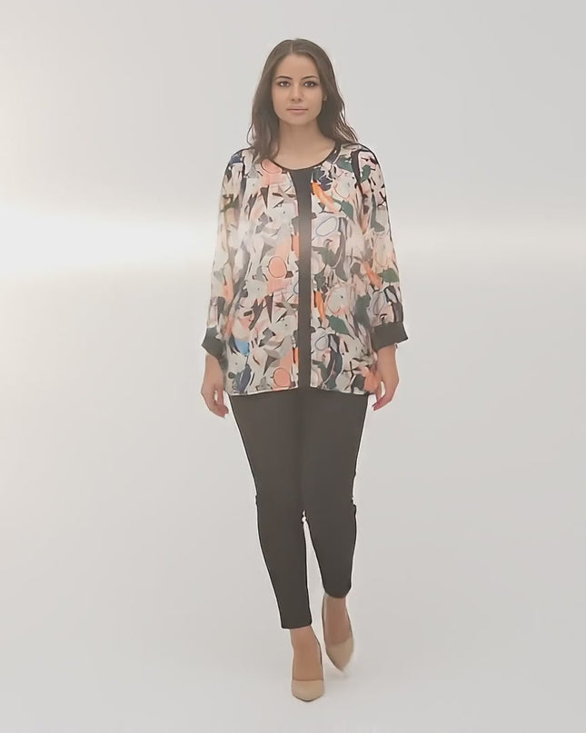 Ένα plus-size μοντέλο περπατάει αργά προς την κάμερα σε περιβάλλον στούντιο με ουδέτερο φόντο φορώντας το προϊόν Στιλάτη τουνίκ με πολύχρωμο σχέδιο σε μεγάλα μεγέθη