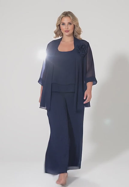 Ένα plus-size μοντέλο περπατάει αργά προς την κάμερα σε ένα στούντιο με ουδέτερο φόντο φορώντας το προϊόν Κομψό Επίσημο Σετ Τριών Τεμαχίων Σκούρο Μπλε Μεγάλα Μεγέθη