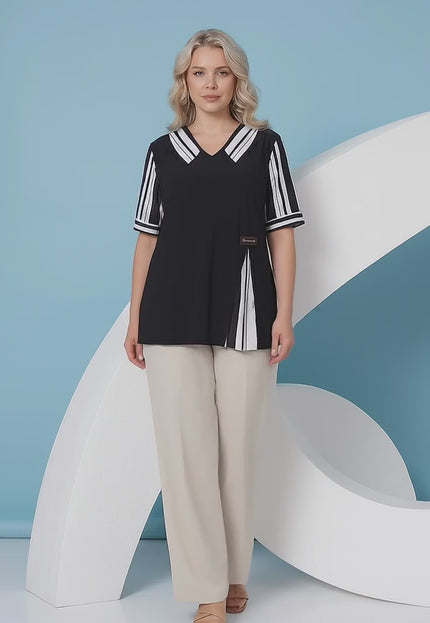 Ένα plus-size γυναικείο μοντέλο περπατάει αργά προς την κάμερα σε περιβάλλον στούντιο με ουδέτερο φόντο φορώντας το προϊόν Επίσημη μαύρη τουνίκ μεγάλα μεγέθη με ριγέ γιακά και κοντό μανίκι