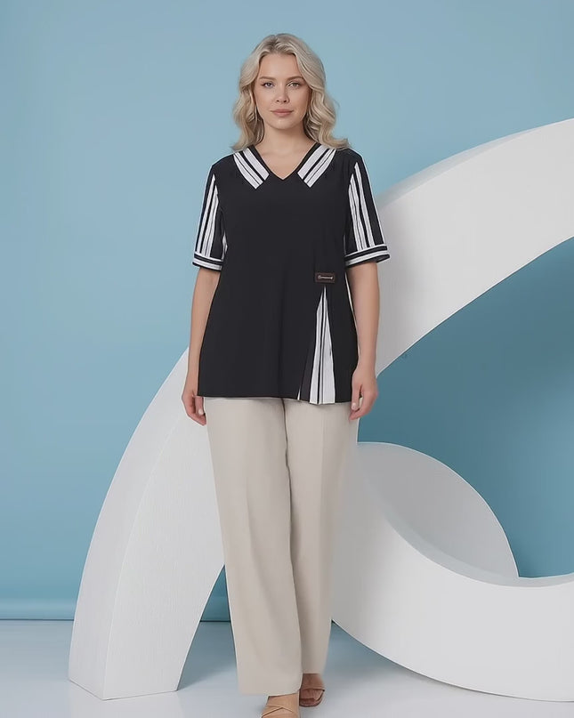 Ένα plus-size γυναικείο μοντέλο περπατάει αργά προς την κάμερα σε περιβάλλον στούντιο με ουδέτερο φόντο φορώντας το προϊόν Επίσημη μαύρη τουνίκ μεγάλα μεγέθη με ριγέ γιακά και κοντό μανίκι