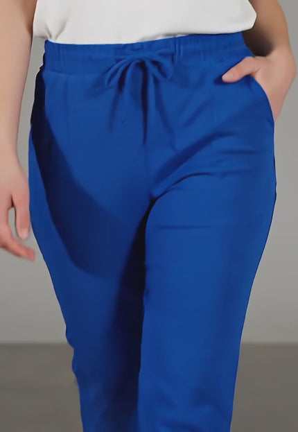 Βίντεο παρουσίασης σε στούντιο όπου ένα plus-size μοντέλο περπατάει αργά προς την κάμερα φορώντας το προϊόν Γυναικείο παντελόνι ρουά με λάστιχο και κορδόνια σε μεγάλα μεγέθη