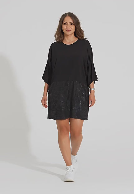 Σε περιβάλλον στούντιο ένα plus-size γυναικείο μοντέλο περπατάει αργά προς την κάμερα φορώντας το προϊόν Κομψή Μαύρη Τουνίκ με  Κορδόνια