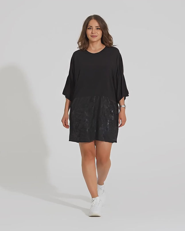 Σε περιβάλλον στούντιο ένα plus-size γυναικείο μοντέλο περπατάει αργά προς την κάμερα φορώντας το προϊόν Κομψή Μαύρη Τουνίκ με  Κορδόνια