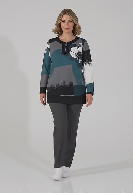 Ένα plus size γυναικείο μοντέλο περπατάει αργά προς την κάμερα σε περιβάλλον στούντιο με ουδέτερο φόντο φορώντας το προϊόν Καθημερινή πολύχρωμη τουνίκ μεγάλα μεγέθη με φερμουάρ