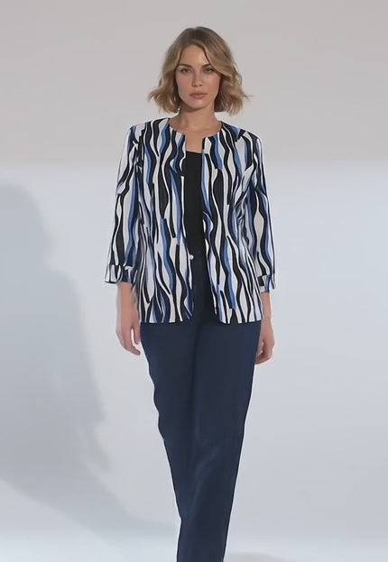 Ένα plus-size γυναικείο μοντέλο περπατάει αργά προς την κάμερα σε περιβάλλον στούντιο με ουδέτερο φόντο φορώντας το προϊόν Γυναικείο επίσημο σακάκι μεγάλα μεγέθη λευκό με μπλε και μαύρα μοτίβα