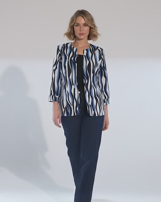 Ένα plus-size γυναικείο μοντέλο περπατάει αργά προς την κάμερα σε περιβάλλον στούντιο με ουδέτερο φόντο φορώντας το προϊόν Γυναικείο επίσημο σακάκι μεγάλα μεγέθη λευκό με μπλε και μαύρα μοτίβα