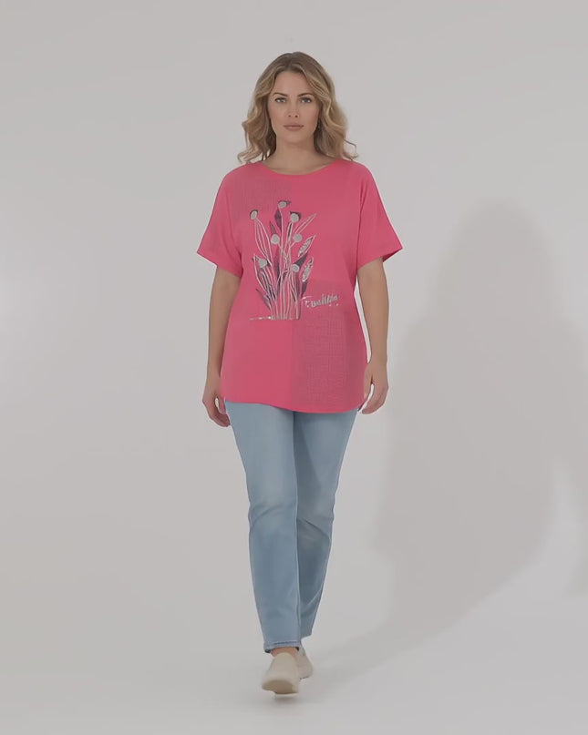 Ένα μοντέλο σε περιβάλλον στούντιο με ουδέτερο φόντο περπατάει αργά προς την κάμερα φορώντας το προϊόν Γυναικεία καλοκαιρινή κοραλί τουνίκ plus size με φλοράλ λεπτομέρειες