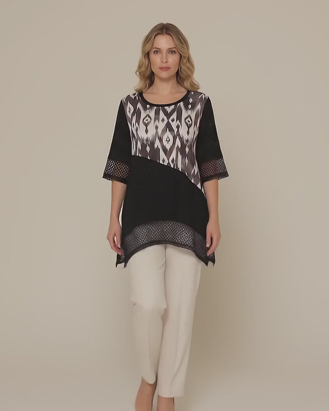 Ένα plus-size μοντέλο περπατάει αργά προς την κάμερα σε περιβάλλον στούντιο με ουδέτερο φόντο φορώντας το προϊόν Επίσημη μαύρη τουνίκ μεγάλα μεγέθη με ασύμμετρη γραμμή και δίχτυ