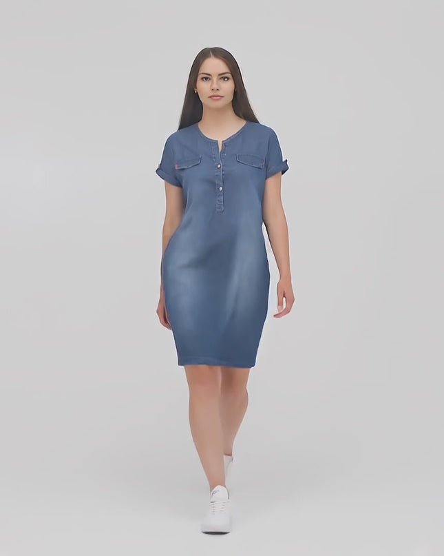 Ένα plus-size μοντέλο περπατάει αργά προς την κάμερα σε περιβάλλον στούντιο φορώντας το Φόρεμα Τζιν- Σκούρο Μπλε - V-λαιμόκοψη - Κουμπιά- Άνοιξη-Καλοκαίρι