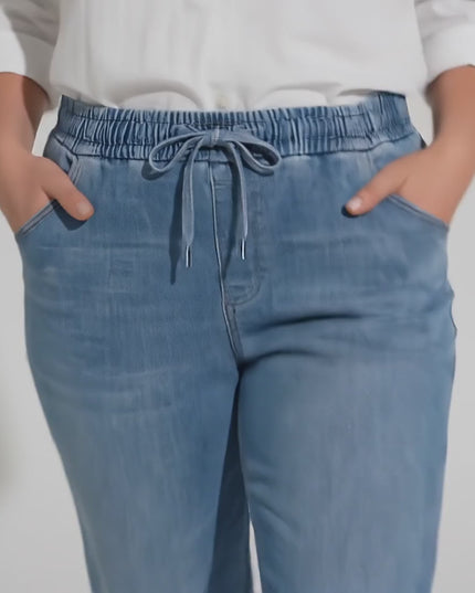 Βίντεο παρουσίασης σε στούντιο με ουδέτερο φόντο όπου ένα plus size γυναικείο μοντέλο περπατάει αργά προς την κάμερα φορώντας το προϊόν Μπλε γυναικείο τζιν με λάστιχο και κορδόνι από tencel και βαμβάκι