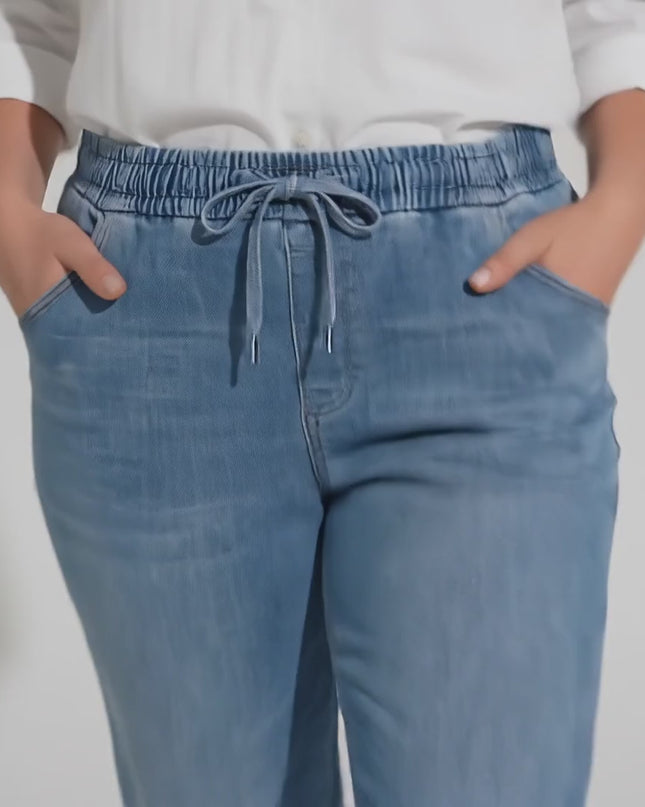 Βίντεο παρουσίασης σε στούντιο με ουδέτερο φόντο όπου ένα plus size γυναικείο μοντέλο περπατάει αργά προς την κάμερα φορώντας το προϊόν Μπλε γυναικείο τζιν με λάστιχο και κορδόνι από tencel και βαμβάκι