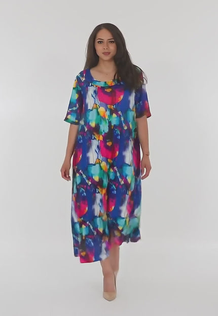 Βίντεο παρουσίασης σε περιβάλλον στούντιο με ουδέτερο φόντο όπου ένα plus-size μοντέλο περπατάει αργά προς την κάμερα φορώντας το προϊόν Πολύχρωμο μακρύ φόρεμα με στρογγυλή λαιμόκοψη