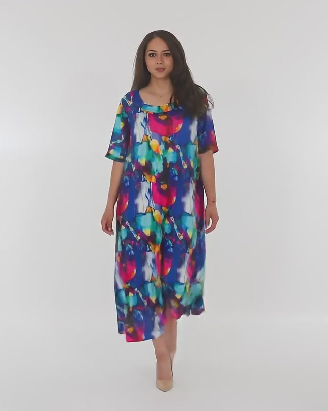 Βίντεο παρουσίασης σε περιβάλλον στούντιο με ουδέτερο φόντο όπου ένα plus-size μοντέλο περπατάει αργά προς την κάμερα φορώντας το προϊόν Πολύχρωμο μακρύ φόρεμα με στρογγυλή λαιμόκοψη