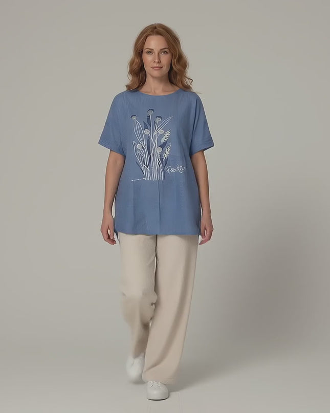 Βίντεο παρουσίασης σε περιβάλλον στούντιο με ουδέτερο φόντο όπου ένα plus size μοντέλο περπατάει αργά προς την κάμερα φορώντας το προϊόν Μπλε καλοκαιρινή τουνίκ μεγάλα μεγέθη με δαντέλα και λουλούδια