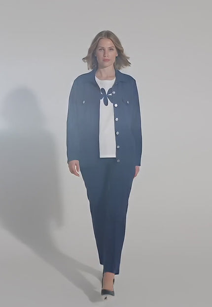 Ένα plus-size γυναικείο μοντέλο περπατάει αργά προς την κάμερα σε περιβάλλον στούντιο με ουδέτερο φόντο φορώντας το προϊόν Επίσημο γυναικείο σετ σακάκι και t-shirt μεγάλα μεγέθη σε μπλε