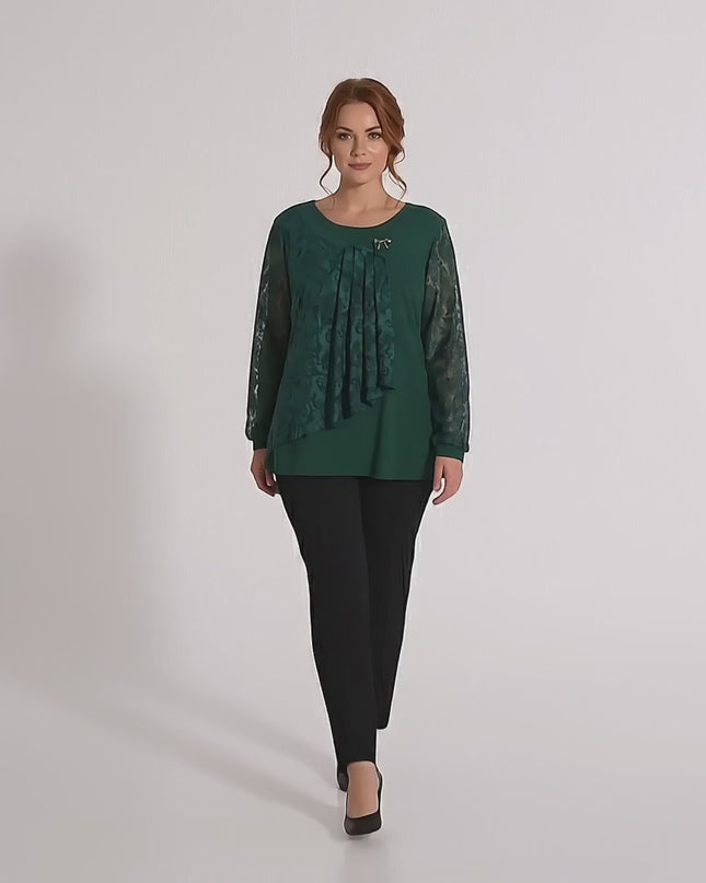 Ένα plus size μοντέλο περπατάει αργά προς την κάμερα σε περιβάλλον στούντιο φορώντας Επίσημη λαδί τουνίκ με δαντελένια μανίκια και καρφίτσα