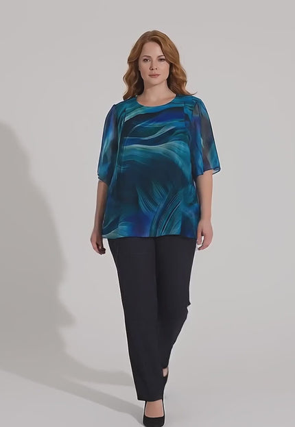 Ένα plus-size γυναικείο μοντέλο περπατάει αργά προς την κάμερα σε περιβάλλον στούντιο με ουδέτερο φόντο φορώντας το προϊόν Επίσημη μπλε τουνίκ σιφόν με αφηρημένο σχέδιο και αέρινη γραμμή