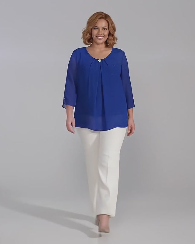 Βίντεο παρουσίασης σε στούντιο με ουδέτερο φόντο όπου ένα plus size μοντέλο περπατάει αργά προς την κάμερα φορώντας την Επίσημη εβαζέ τουνίκ σιφόν σε μπλε ρουά με καρφίτσα