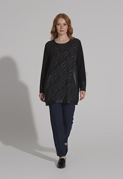 Ένα plus-size γυναικείο μοντέλο περπατάει αργά προς την κάμερα σε περιβάλλον στούντιο φορώντας το προϊόν Επίσημη μαύρη τουνίκ με τσέπες και λεπτομέρειες από δερματίνη