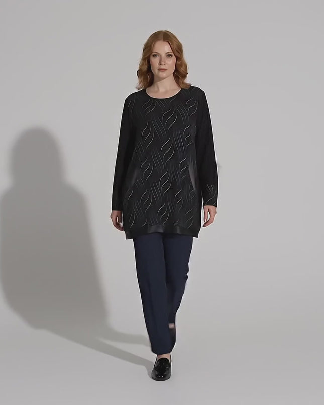 Ένα plus-size γυναικείο μοντέλο περπατάει αργά προς την κάμερα σε περιβάλλον στούντιο φορώντας το προϊόν Επίσημη μαύρη τουνίκ με τσέπες και λεπτομέρειες από δερματίνη